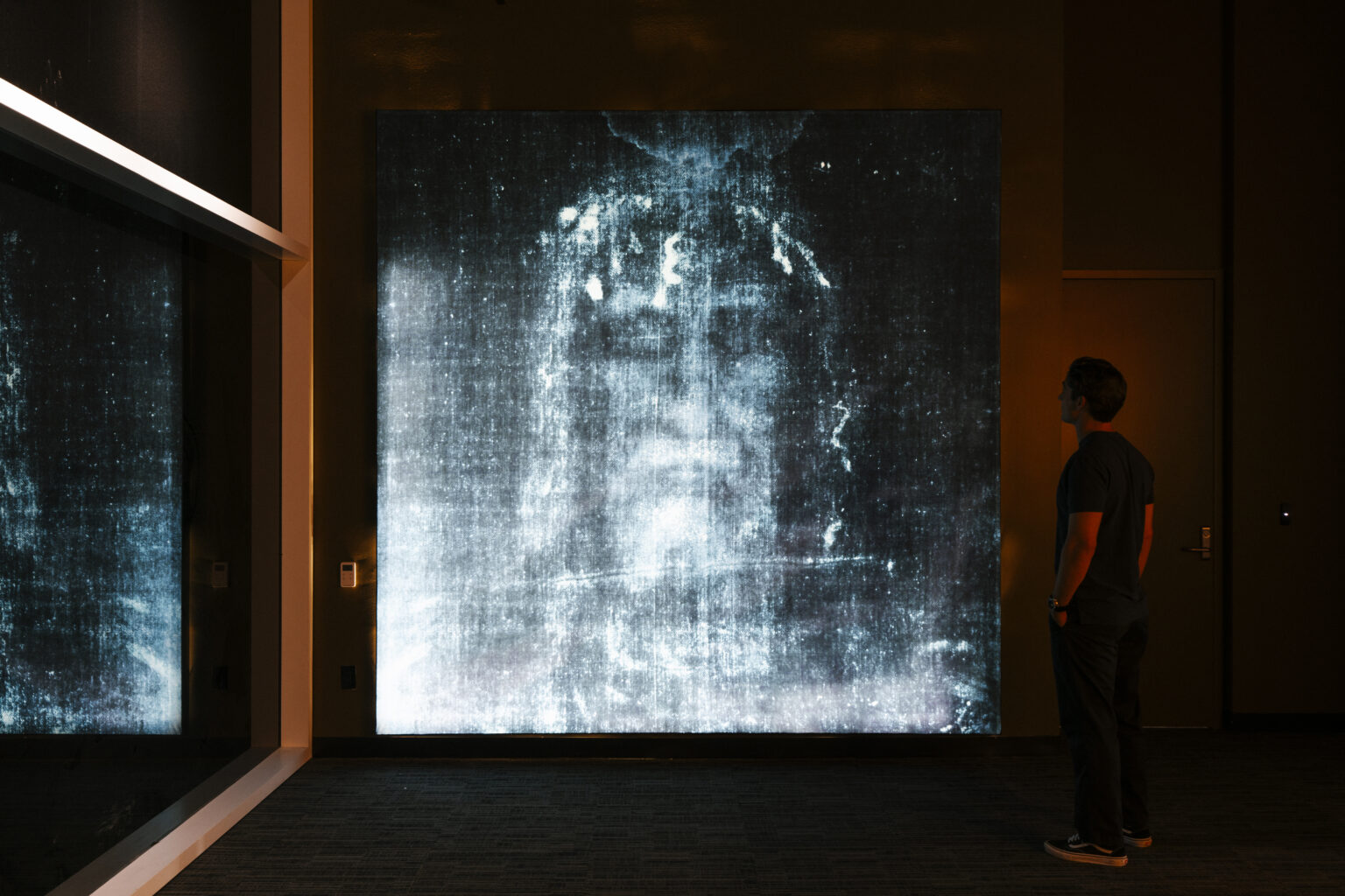 A visitor studying the photographic negative of the face on the Shroud