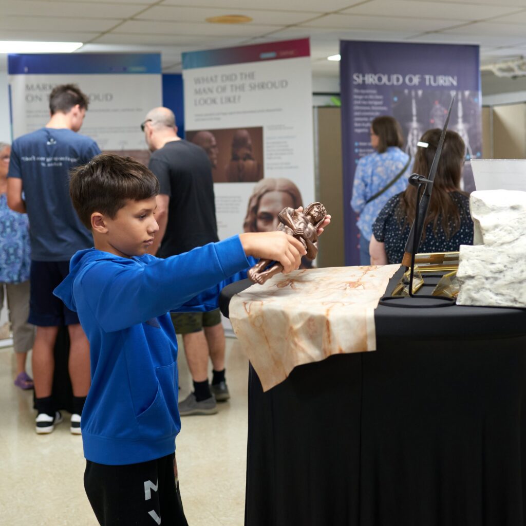 Child touching a replica artifact at the Shroud exhibit