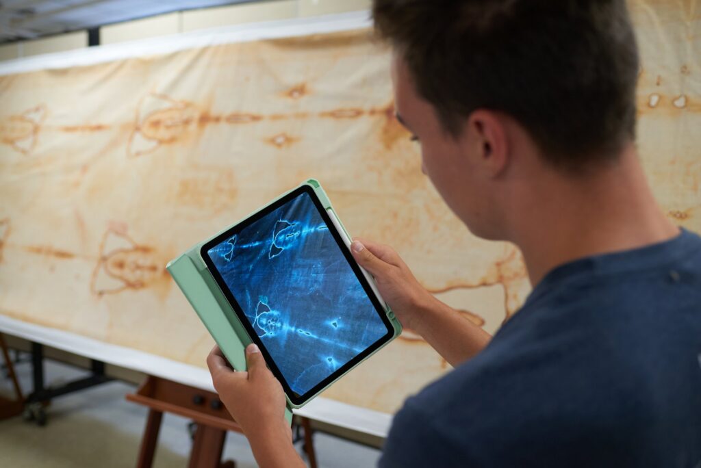 Young visitor viewing the Shroud as a photo negative on a tablet